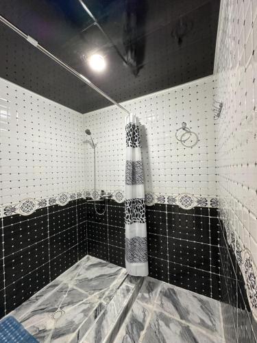 a bathroom with a shower with black and white tiles at MusoBarakaNur Guest House in Yukary-Ukhum