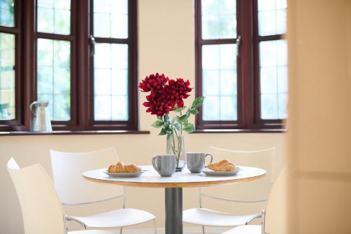 a table with a vase of red flowers and croissants at Spacious Home for Large Families and Contractors in Wolverhampton