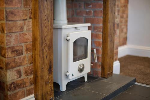 a white wood stove in a brick wall at Spacious Home for Large Families and Contractors in Wolverhampton