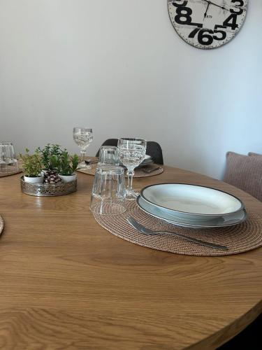 a table with plates and glasses and a clock on the wall at Apartman Gaby in Virovitica
