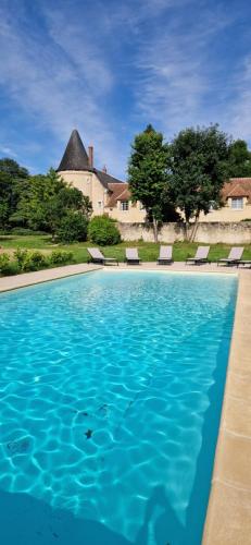 une piscine avec des chaises et une maison en arrière-plan dans l'établissement Domaine du Prieuré de Saint Martin à Lavardin, à Lavardin