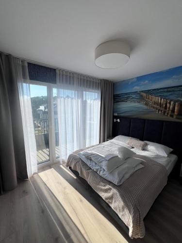 a bedroom with a large bed and a large window at Apartamenty MIW Dziwnów 21 in Dziwnów