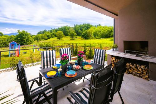 a table with chairs on a patio with a fireplace at Residence Villa Manuela with Pool & Jacuzzi - Batlug in Batlug