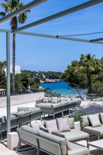 a row of lounge chairs on a patio with a view of the ocean at Hotel Rocamarina - Adults Only in Cala d´Or