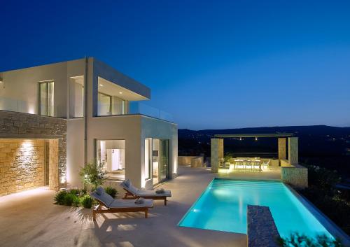 a villa with a swimming pool at night at Youphoria Sea View Villas in Kissamos