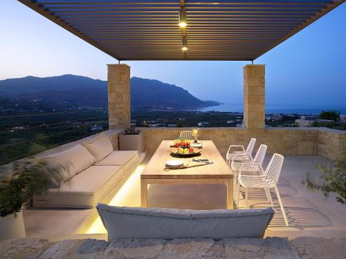 a patio with a couch and a table and chairs at Youphoria Sea View Villas in Kissamos