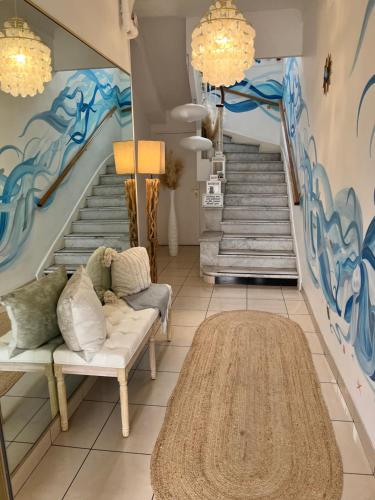 a living room with a staircase with a mural at Hôtel Eden - La Baigneuse in Juan-les-Pins