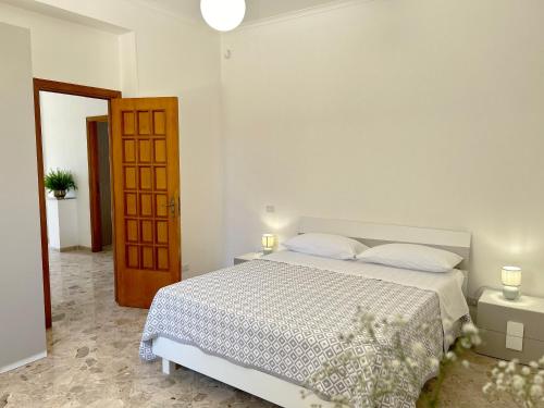 a white bedroom with a bed and a wooden door at Villa Sole near the sandy beach, parking & wifi in Avola