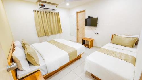 a hotel room with two beds and a television at Hotel Nova Safal in Rajkot