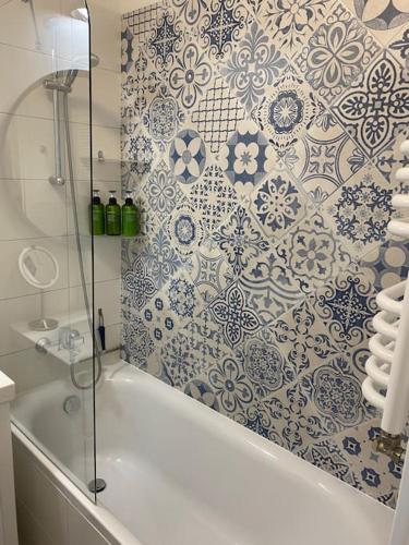 a bathroom with a shower with a blue and white tiles at Cozy City Appartement Warszawa in Warsaw