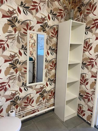 a mirror in a bathroom with a floral wallpaper at Au rythme des Ferrys in Calais