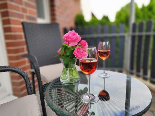 two glasses of wine and a vase with flowers on a table at Apartment Marissa in Billerbeck