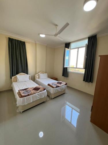 Dos camas en una habitación con dos ventanas. en الحى التجارى RED-13 ALhaddad, en Salalah