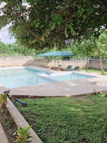 a swimming pool with a table and an umbrella at Jade luxury apartments Diani in Mombasa