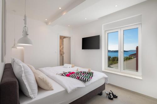 a white bedroom with a bed and a window at Villa Porto in Ražanj
