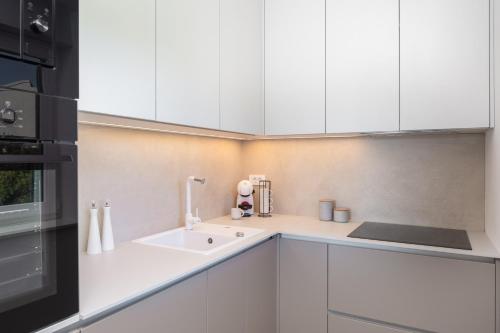 a kitchen with white cabinets and a sink at Villa Porto in Ražanj