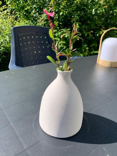 a white vase with a flower in it sitting on a table at Durbuy Dream in Durbuy