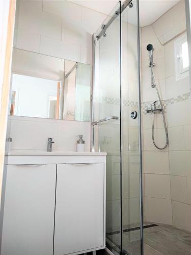 La salle de bains est pourvue d'une douche et d'un lavabo blanc. dans l'établissement Appartement T2 neuf vue mer en bord de mer, à Six-Fours-les-Plages