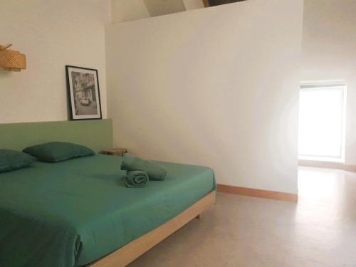 a bedroom with a green bed and a window at La Maison Emilie in Villeneuve-dʼAveyron