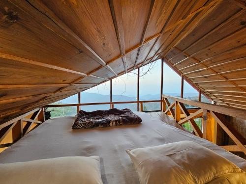 a large bed in a wooden room with windows at The Vanya, Boutique Stay in Rāmgarh