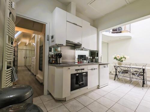 une cuisine avec des appareils blancs et une table dans une pièce dans l'établissement L'appartement d'Henri - Place Vendôme, à Paris