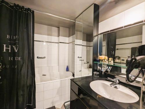 une salle de bain avec un lavabo, une baignoire et un miroir dans l'établissement L'appartement d'Henri - Place Vendôme, à Paris