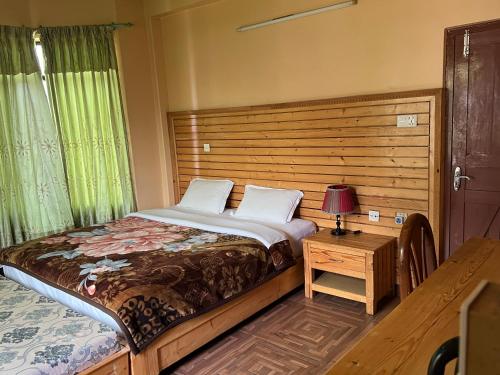 ein Schlafzimmer mit einem Bett und einem Tisch mit einer Lampe in der Unterkunft Hotel Diplomat in Pokhara