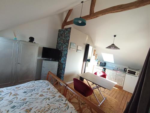 a bedroom with a bed and a table and a kitchen at Domaine de la Dolce Vita de Gaudreville la rivière in Gaudreville-la-Rivière