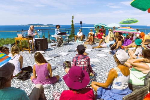 a group of people sitting on the beach listening to a speaker at ClaudiAgapi Apartments Korfu in Agios Stefanos