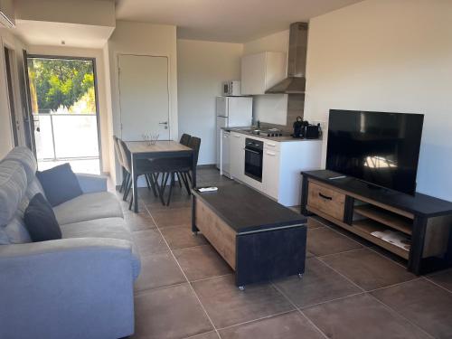 un salon avec un canapé et une table et une cuisine dans l'établissement T2 Porticcio neuf, à Porticcio