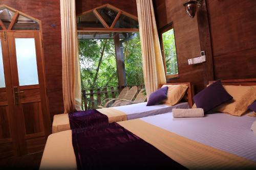 dwa łóżka w pokoju z oknem w obiekcie River Face Inn w mieście Tissamaharama