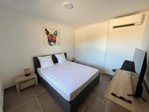 une chambre avec un lit et un bureau avec une télévision dans l'établissement T2 Porticcio neuf, à Porticcio