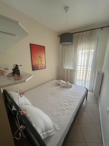 a large bed in a room with a window at Theros Kalamitsa Apartment in Kavála