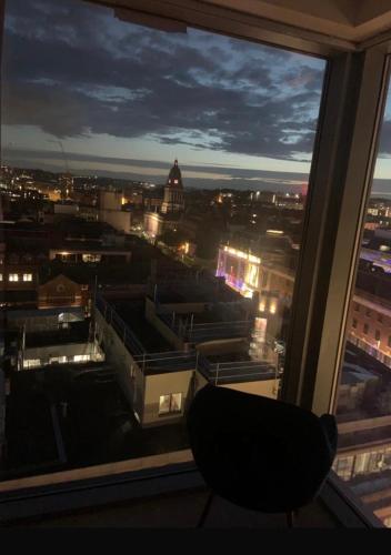 a chair sitting in front of a window at night at Winners of 2025 traveller Award, Elegant two bedroom city central apartment with Netflix & WiFi in Leeds