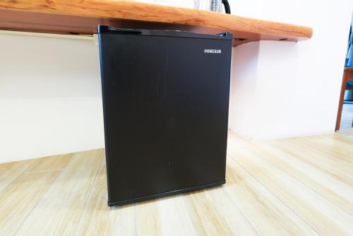a black refrigerator sitting on a wooden floor at Zhaohong homestay in Yuchi