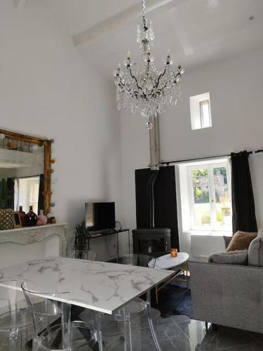 un salon avec une table et un lustre dans l'établissement Appartement proche aéroport & indret, à Bouguenais
