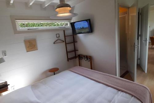 a bedroom with a bed and a tv on the wall at Tuinhuis Vijverzicht in Leeuwarden
