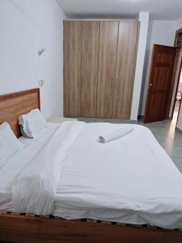 a bedroom with a large white bed with wooden cabinets at Jade luxury apartments in Galu