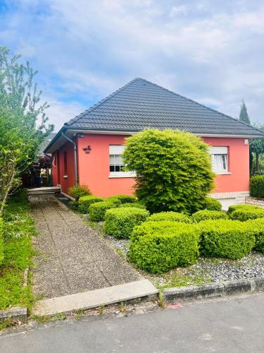 ein rotes Haus mit Büschen davor in der Unterkunft Nice and cozy House in Frisange