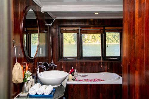 a bathroom with a tub and a sink and two windows at Bhaya Legend Cruises in Ha Long