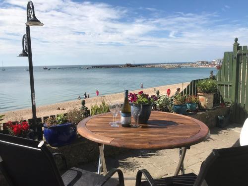 einen Holztisch am Strand mit einer Flasche Wein in der Unterkunft Dolphin Cottage Lyme Regis in Lyme Regis