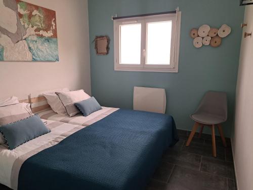 sypialnia z niebieskim łóżkiem i oknem w obiekcie Edith et Jean-Paul w mieście Porto-Vecchio