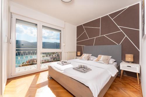 a bedroom with a large bed and a large window at Apartment Stella in Rabac