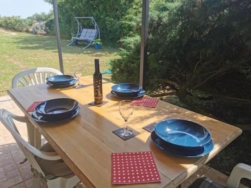 a wooden table with blue bowls and plates on it at Small Robinson House 250m to the sea in Peroj