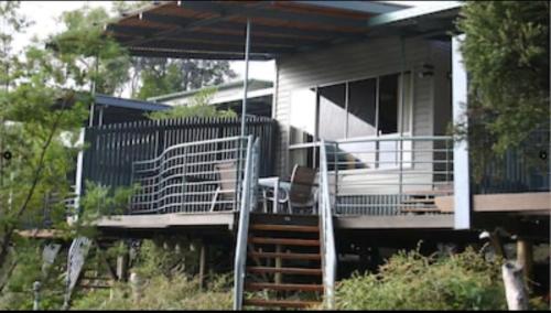 a house with a deck with a chair on it at Sun Set Satinay Executive Villa 615 at Kingfisher Bay Fraser Island in Kingfisher Bay