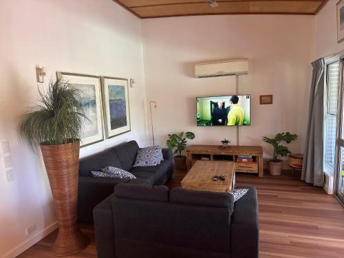 a living room with a couch and a tv at Sun Set Satinay Executive Villa 615 at Kingfisher Bay Fraser Island in Kingfisher Bay