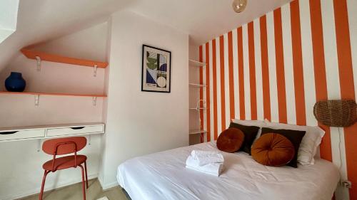 - une chambre avec un lit à rayures orange et blanche dans l'établissement Les toits de Saint-Cyr, à Nevers
