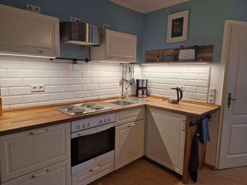 a kitchen with white cabinets and a stove top oven at Business Apartments Netzeband in Netzeband