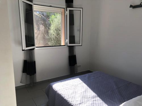 ein Schlafzimmer mit einem Bett und einem Fenster in der Unterkunft MINI VILLA entre mer et montagne PALAVESA in Porto-Vecchio