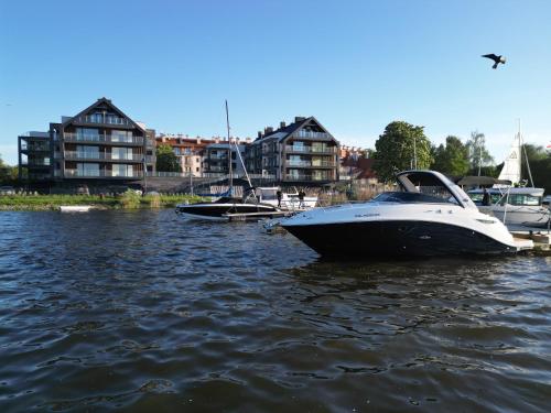 two boats are docked in a river with buildings at Marina Ostróda II - najlepszy widok w Ostródzie in Ostróda